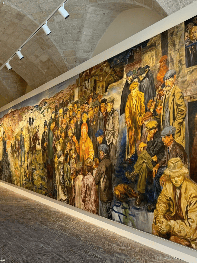 People viewing a large mural painting at an art gallery, showcasing diverse individuals in a historical scene.