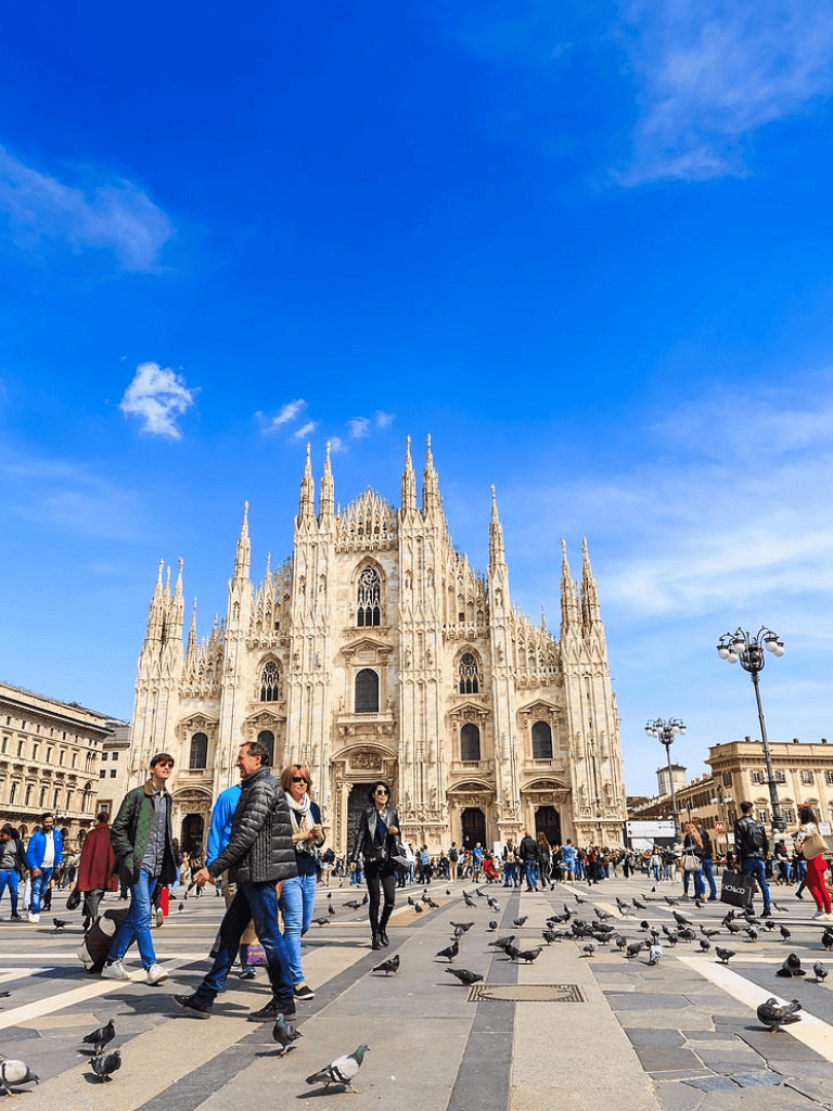 Majestic Milan Cathedral in Italy with tourists and pigeons in Piazza del Duomo.