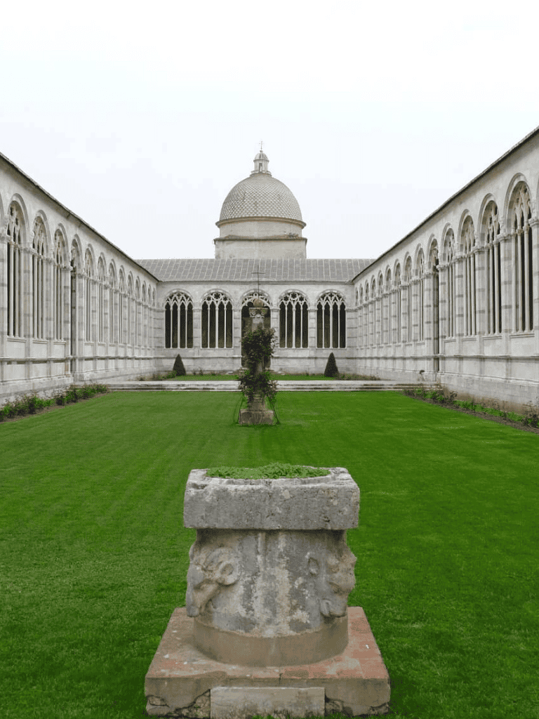 Ancient cloister with lush green garden and historic architecture.