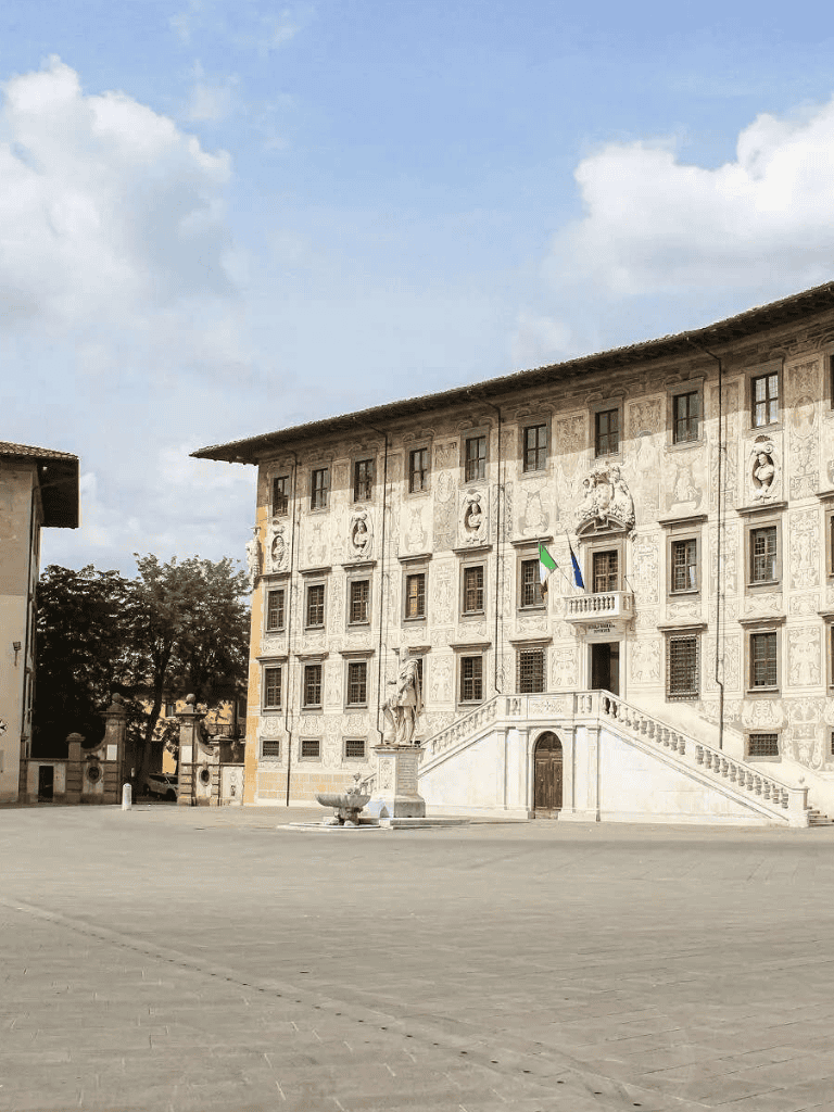 Majestic historic building with ornate facade and Italian flags in Pisa, Italy.