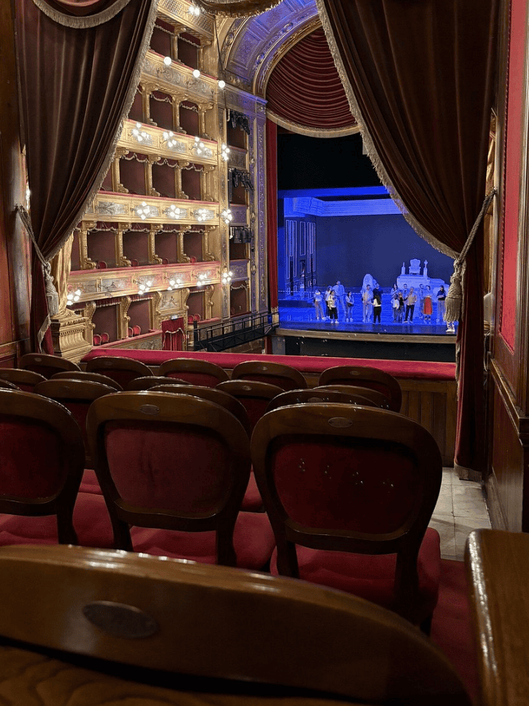 Ornate theater stage with red velvet curtains and plush seating, perfect for performances and live theater experiences.