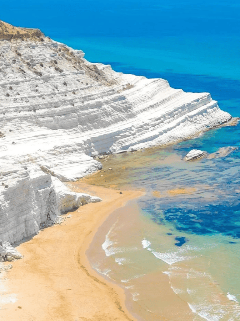 Vibrant coastal landscape with white cliffs, golden beach, and turquoise waters, perfect for travel inspiration.