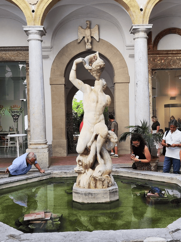 Ancient white marble statue of Neptune in a fountain at QuestForDirections, historic architecture, and visitors.