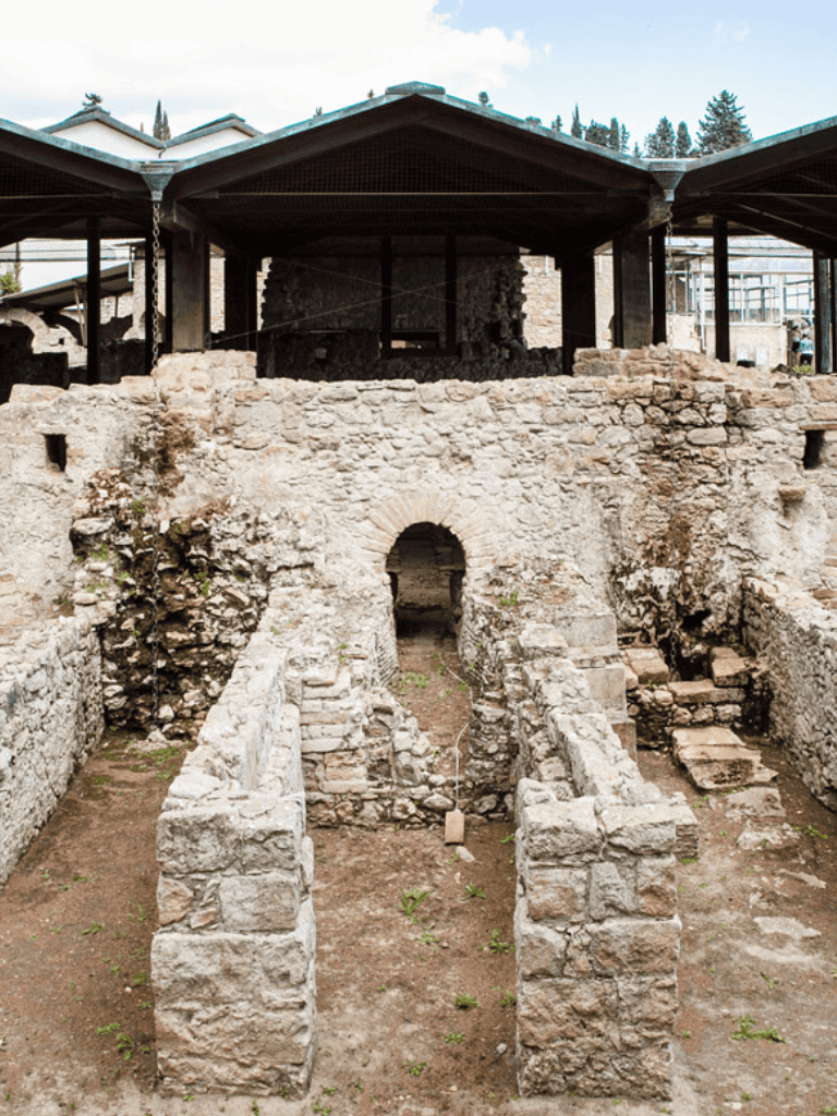 Ancient ruins and archaeological site with stone walls, archway, and stepped pathways.