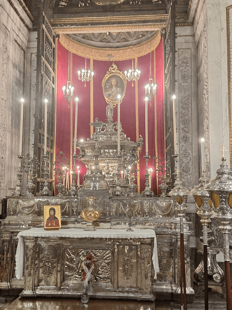 Intricate silver altar with religious icons and candles inside a historic church or chapel.