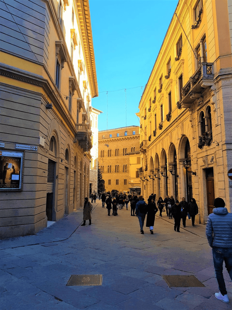 Historic European street with people walking and classic architecture, perfect for city sightseeing.