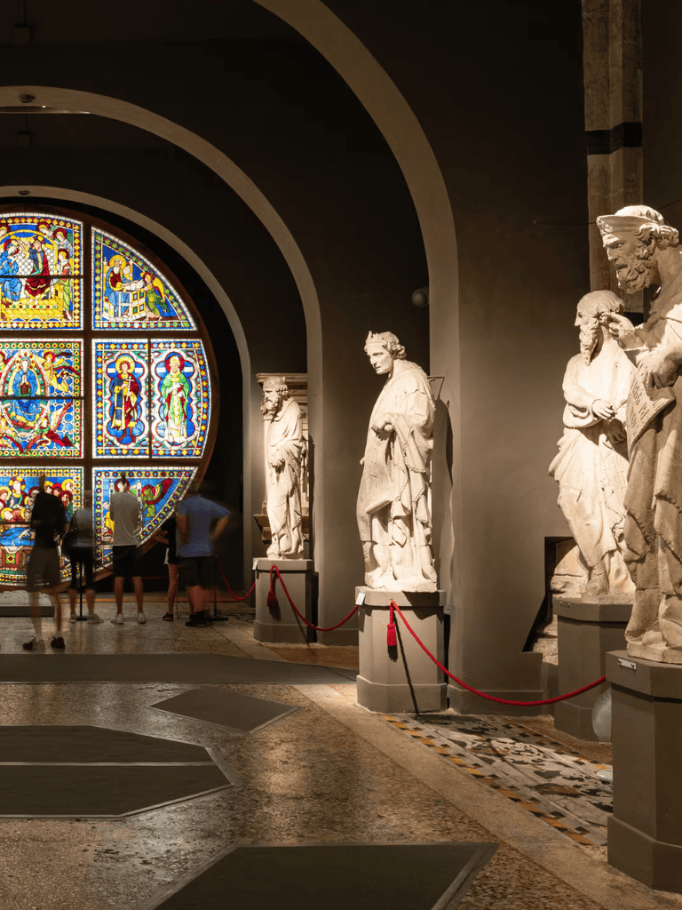 Intricate stained glass window with ancient sculptures at QuestForDirections museum exhibit.