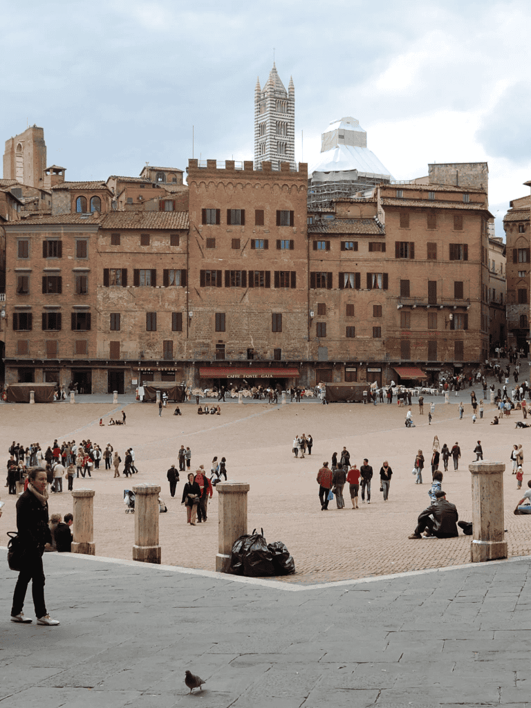Ancient city square in Florence with historic buildings and tourists enjoying the view.