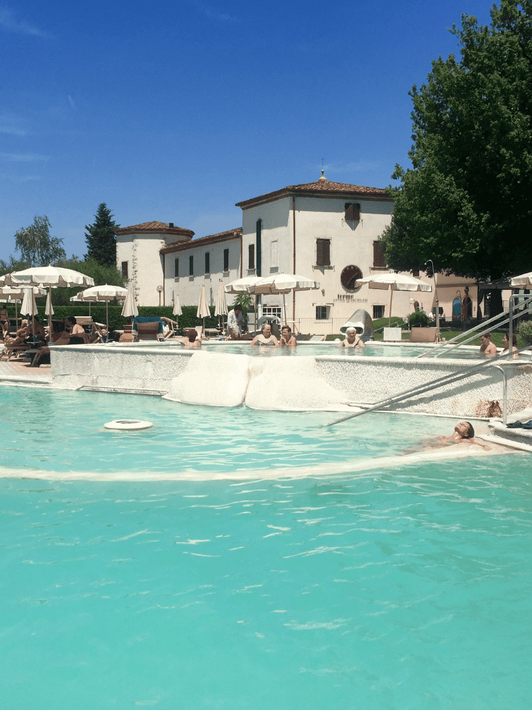 Relaxing pool scene at Quest for Directions resort with lounge chairs and umbrellas in a sunny outdoor setting.