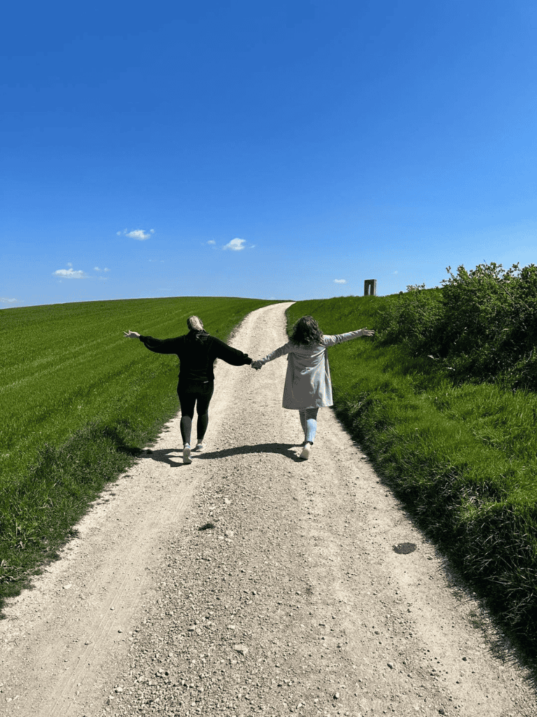 Peaceful countryside, couple holding hands, scenic dirt road, nature escape, travel, relaxation, outdoors, adventure, green fields, blue sky.