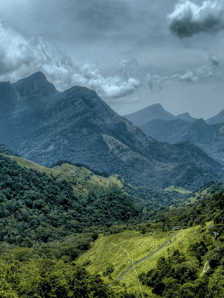 Vibrant mountain landscape with lush greenery and dramatic cloud formations, showcasing adventure and outdoor exploration.