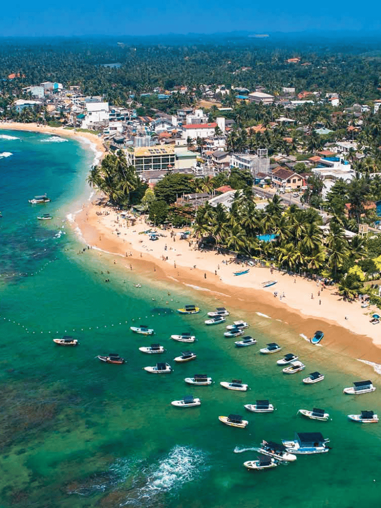 Vibrant coastal town with boats and sandy beach, tropical scenery and lush greenery, perfect for travel and adventures.