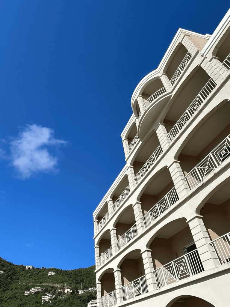 Modern coastal apartment building with multiple balconies under clear blue sky.