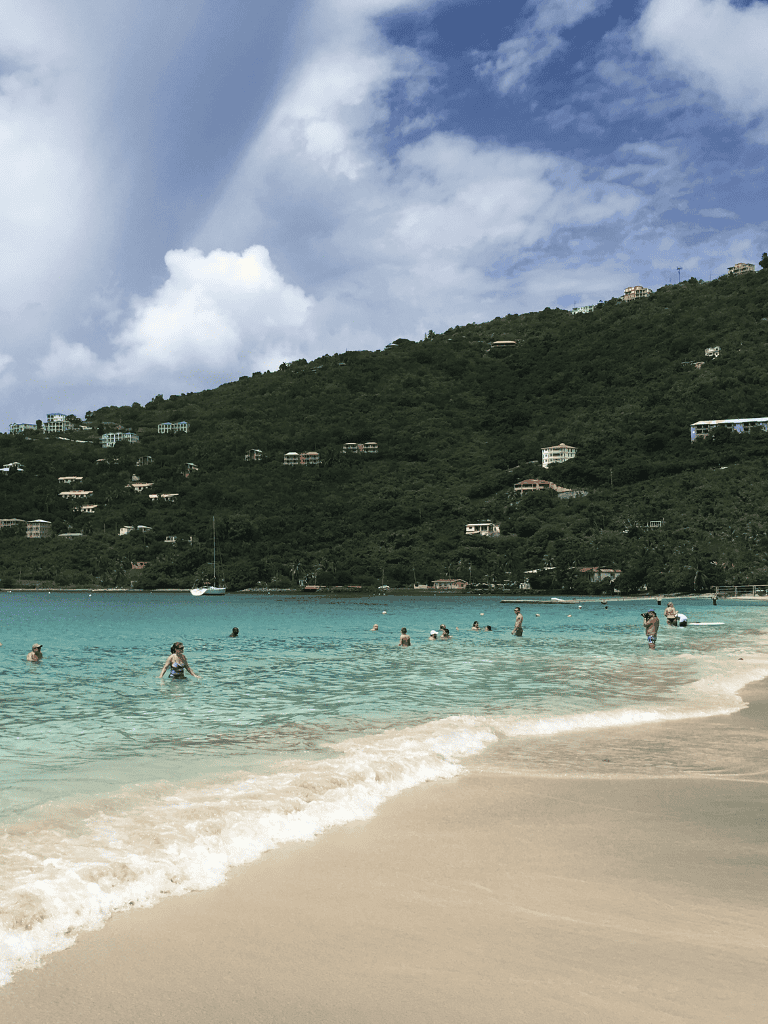 Snorkeling in crystal-clear Caribbean waters with hillside villas in the background.