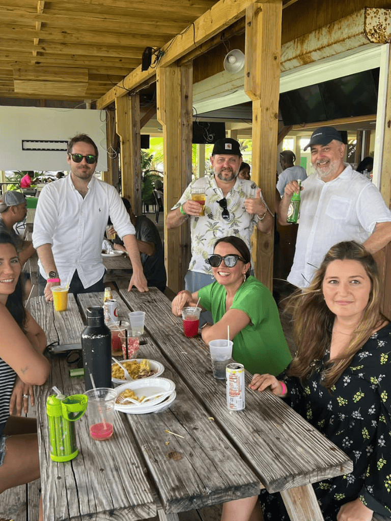 Relaxed group enjoying drinks and food at a tropical outdoor restaurant, lush greenery, and casual vibe.