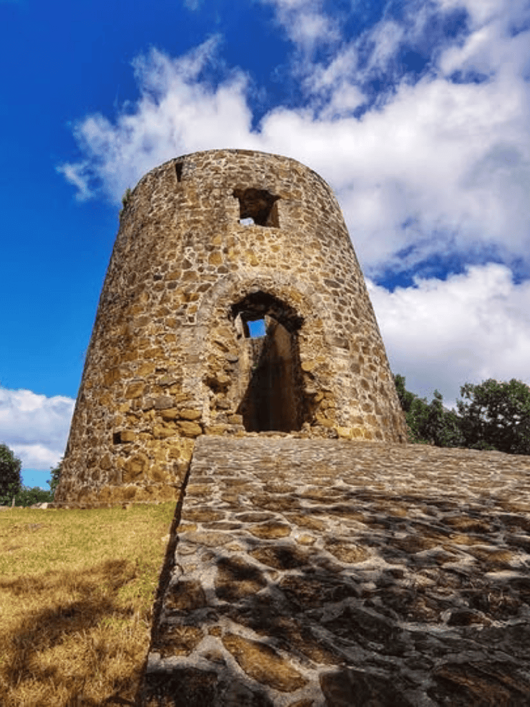 Ancient stone tower surrounded by blue sky and clouds, historical landmark for travel and exploration.
