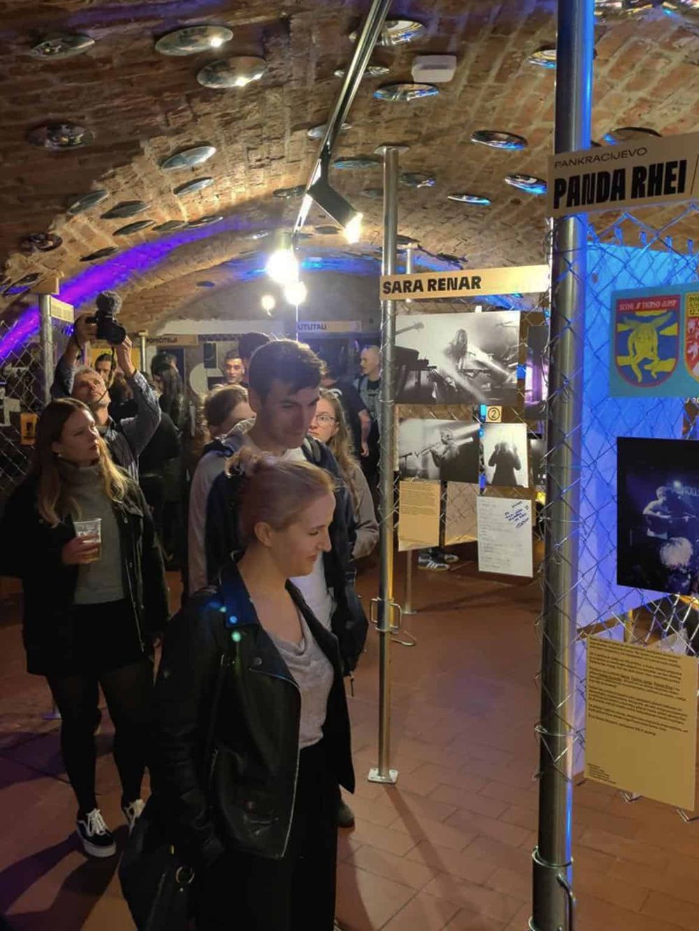 Crowd at an art exhibit showcasing black and white photographs in a historic brick venue.