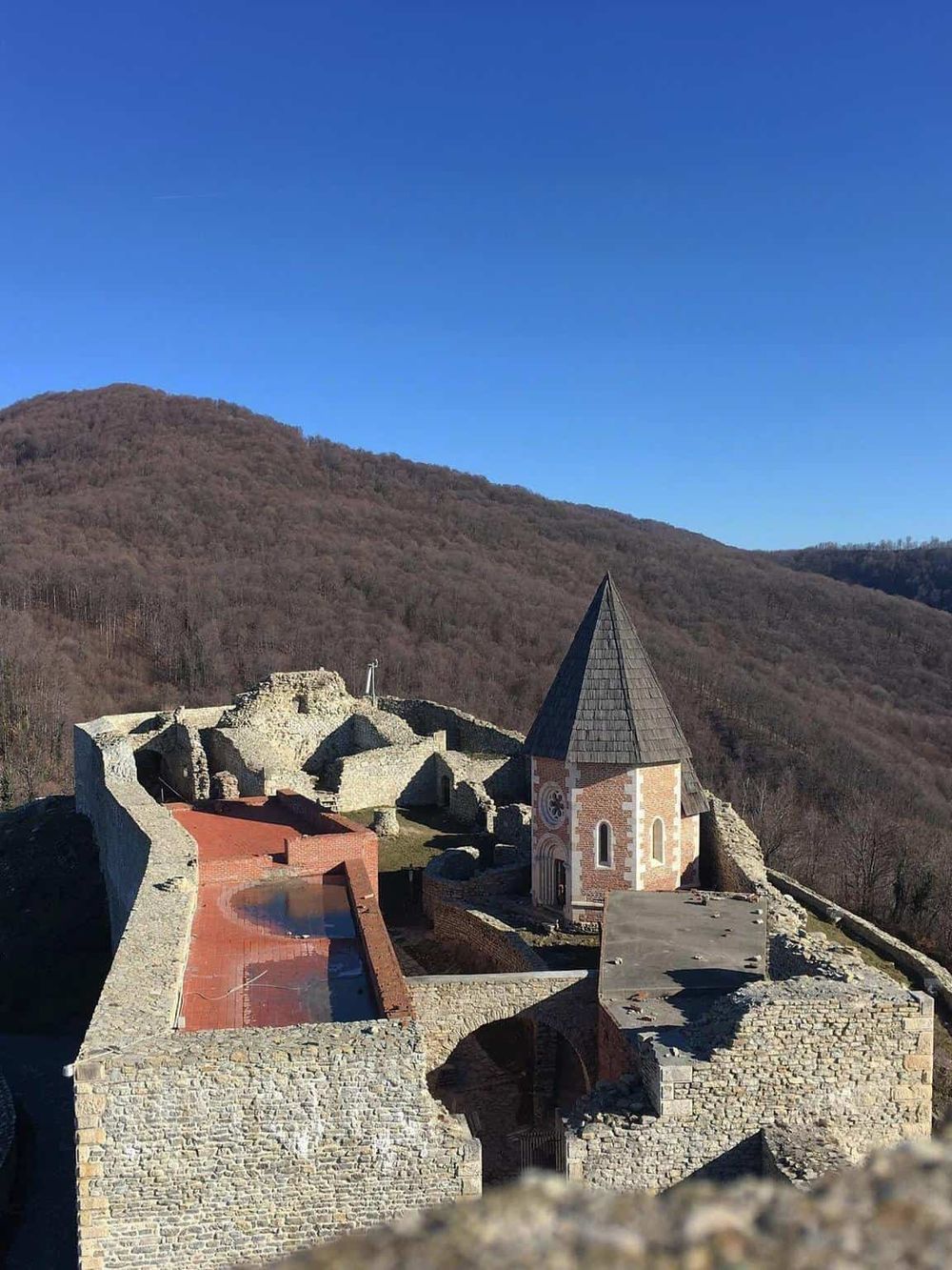 Historic castle ruins with a church and scenic mountain backdrop in Heldenstein, Bavaria, Germany.