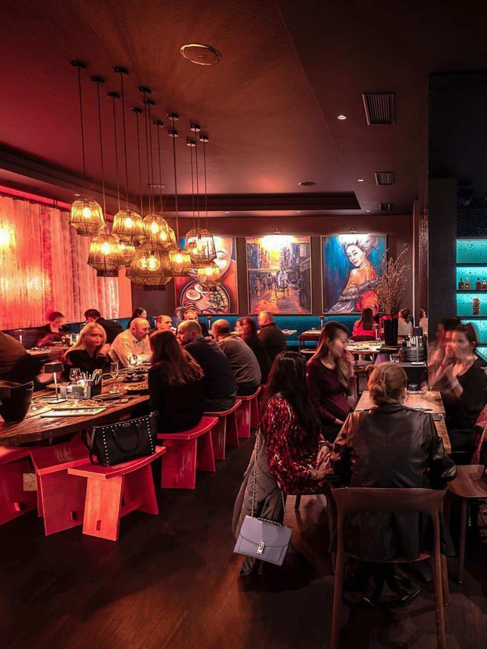Brightly lit modern restaurant interior with diners enjoying meals and vibrant artwork in the background.