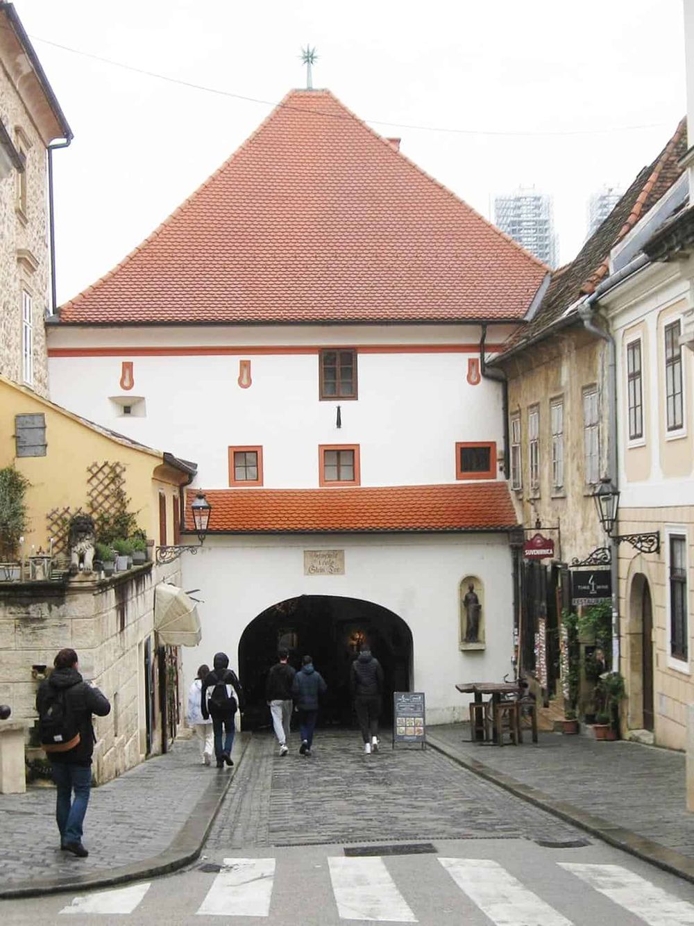 Historic European street scene with a distinctive white building, cobblestone street, and pedestrians, ideal for travel and navigation guides.