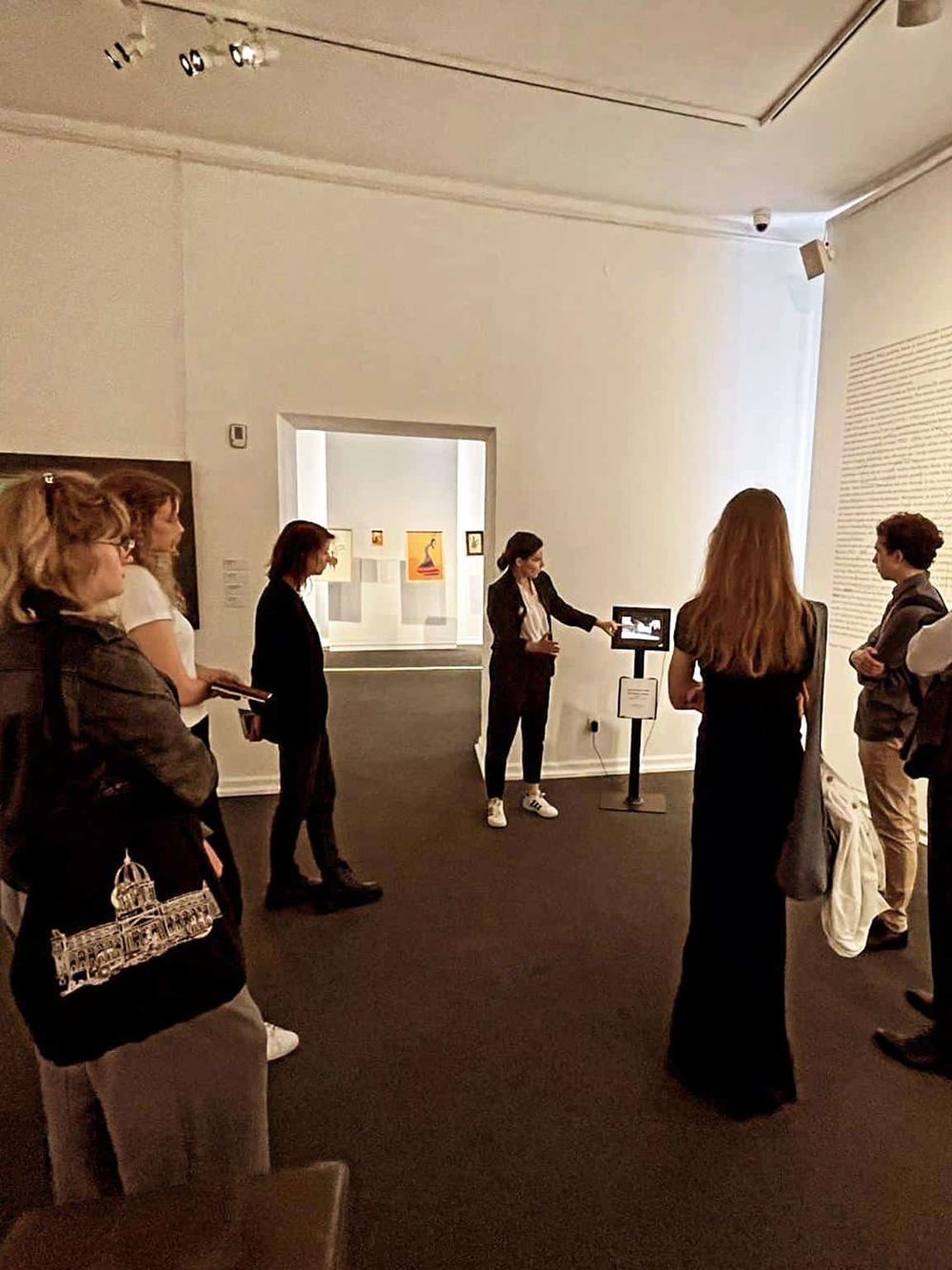 Accessible art exhibit tour with guide explaining artwork to visitors in a gallery setting.