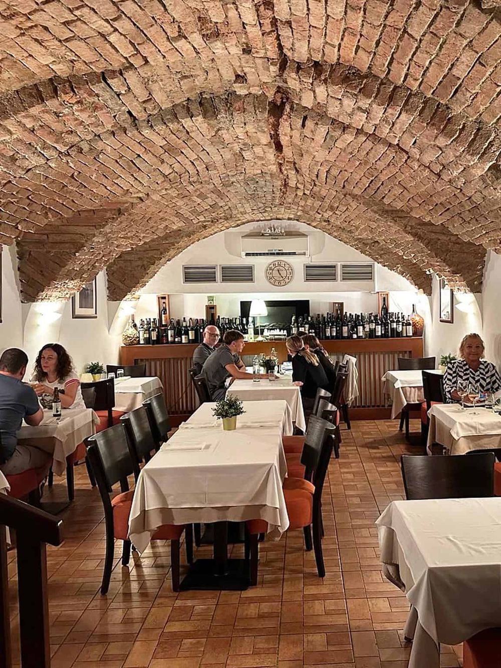 Cozy restaurant with brick vaulted ceiling and elegant dining setup, perfect for a fine dining experience.