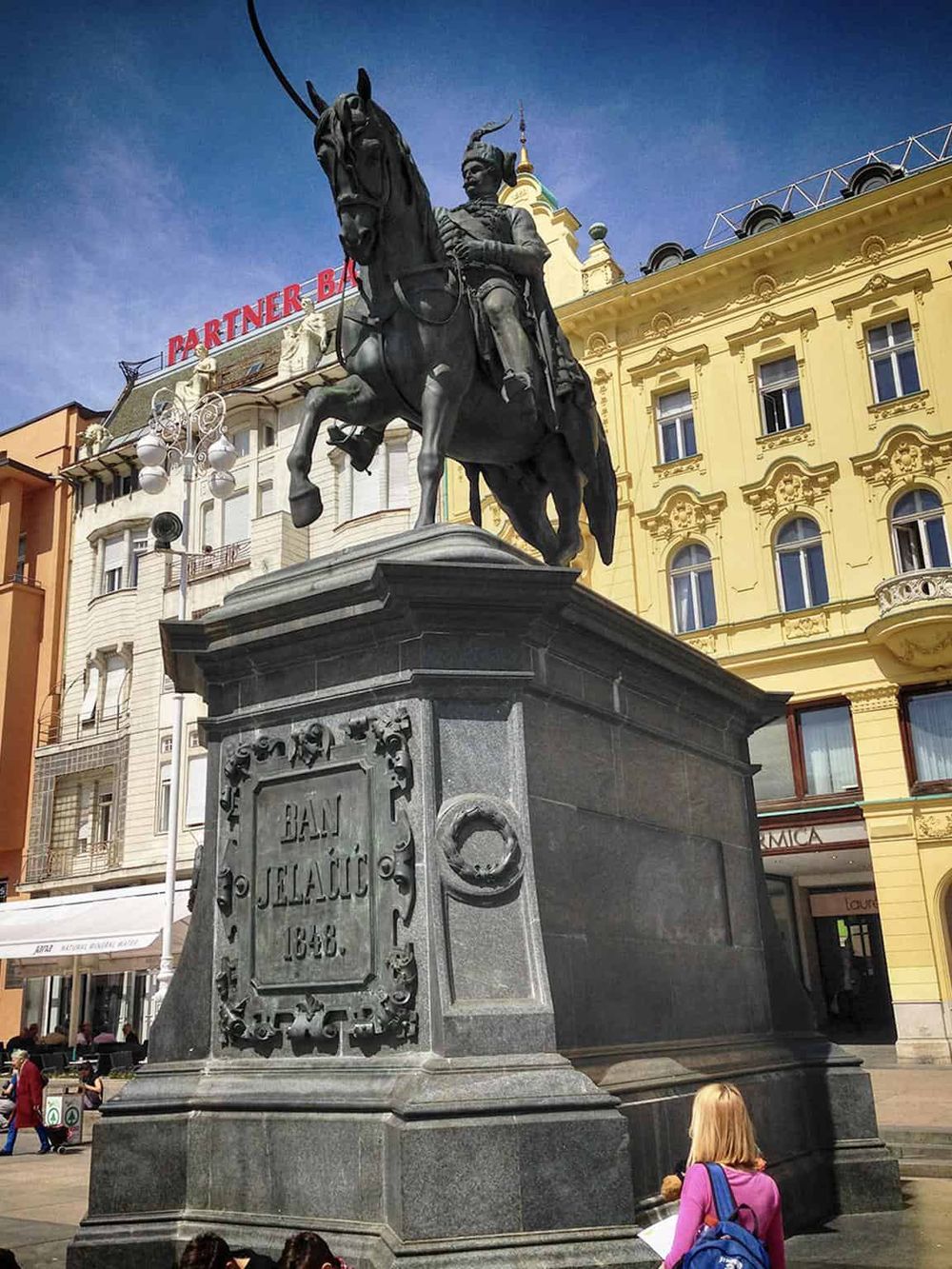 Equestrian statue in a lively city square, highlighting historical landmarks and urban exploration.