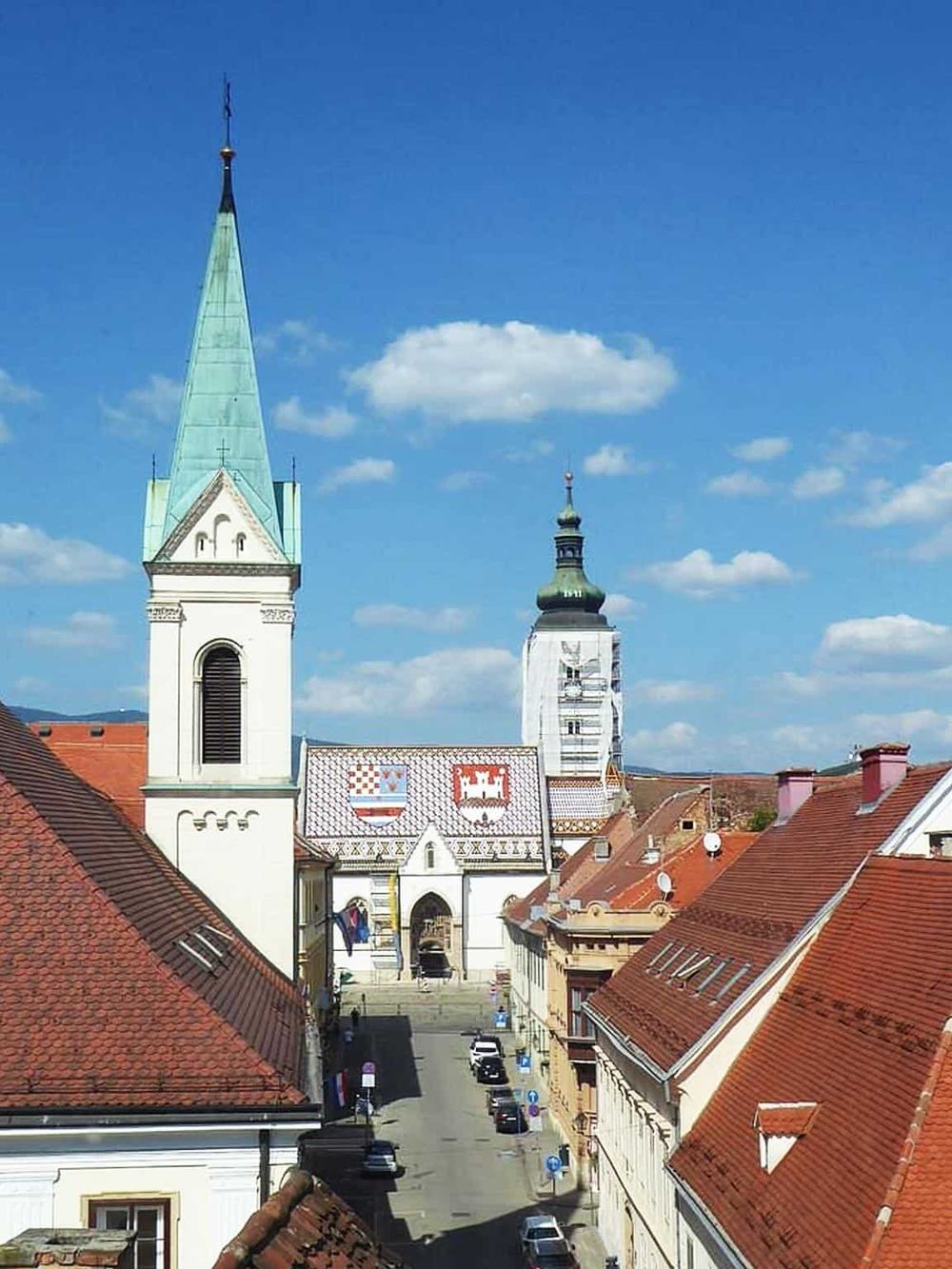 Colorful historic church rooftops in European town, picturesque skyline with blue sky, architecture, travel destination, QuestForDirections.