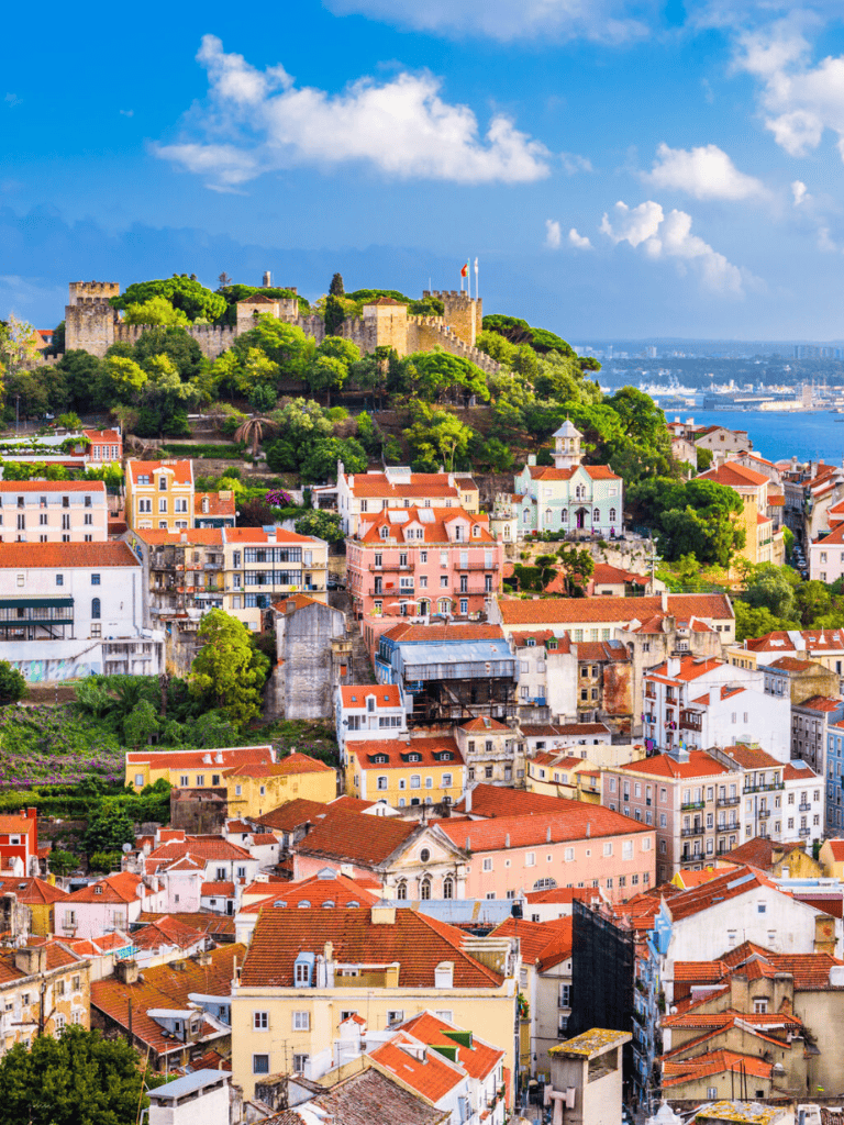 Ancient castle atop colorful hillside neighborhood in Lisbon Portugal.