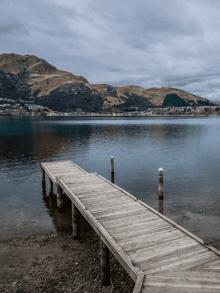 Serene lakeside dock with mountains in the background, perfect for nature exploration and outdoor adventures.