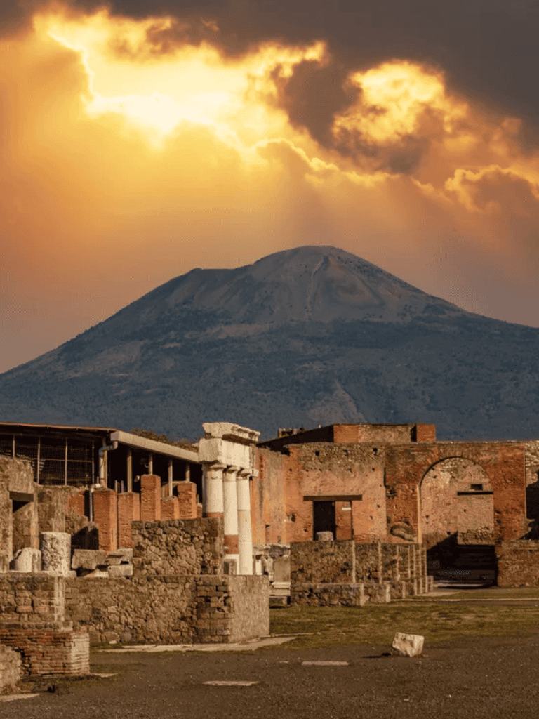 Ancient ruins with Mount Vesuvius in the background during sunset, Italy sightseeing, historical exploration.