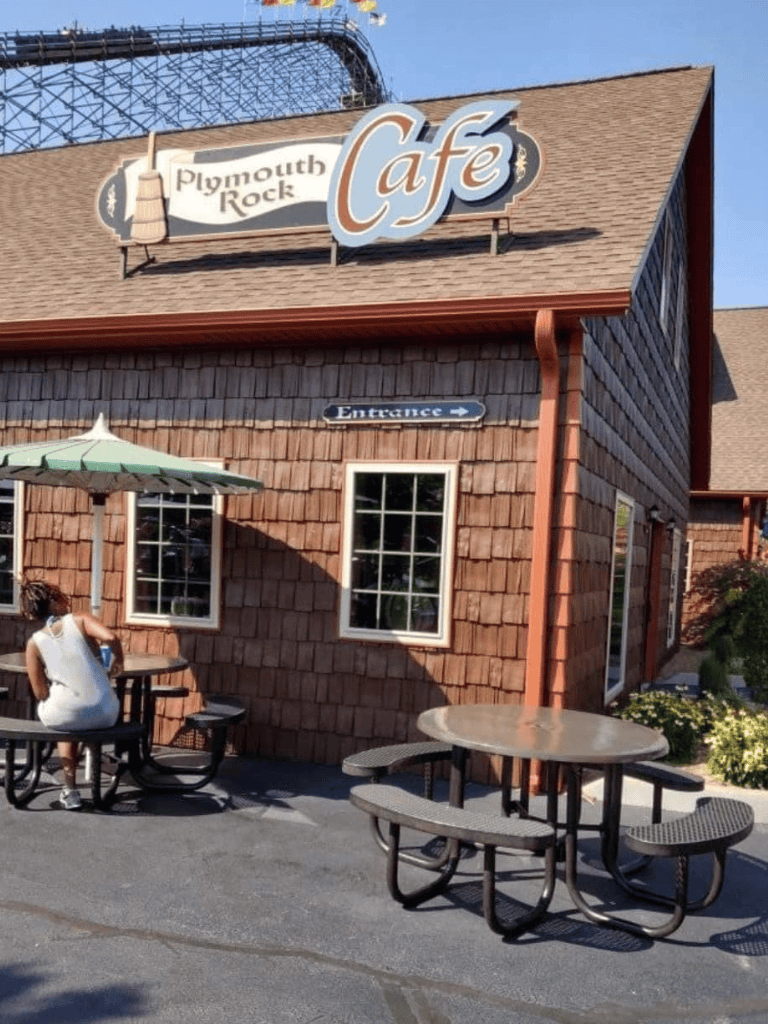Plymouth Rock Cafe exterior with outdoor seating and a woman sitting at a table.