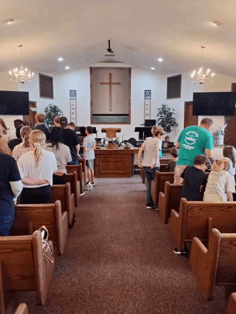 Accessible church interior during worship service with congregation and cross at the altar.