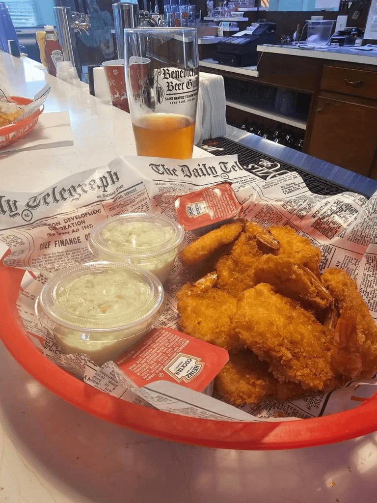 Crispy fried shrimp with coleslaw and beer at a bar, perfect for American comfort food dining.
