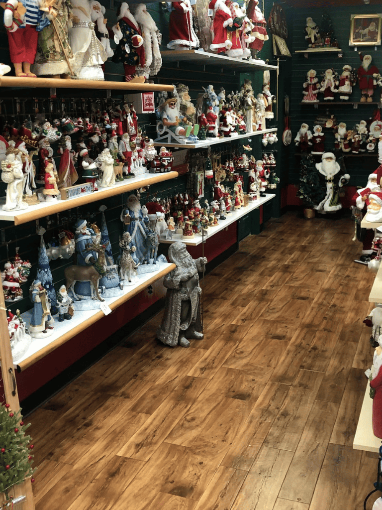 Santa Claus figurines and Christmas decorations on display in a holiday store aisle.