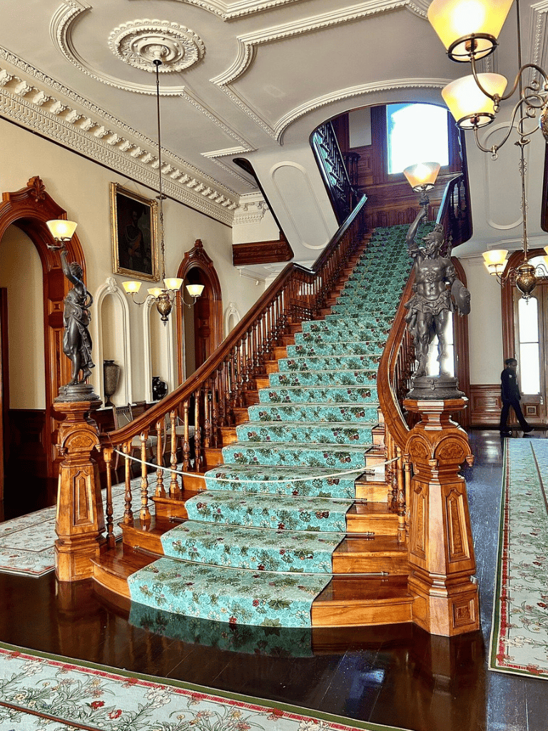 Luxurious grand staircase with ornate woodwork in historic mansion.