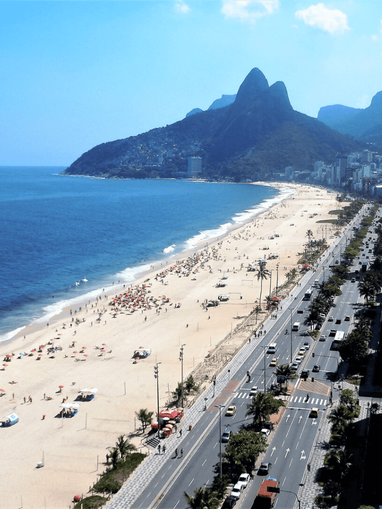 Beach with mountains and cityscape along the coastline in Rio de Janeiro, Brazil.