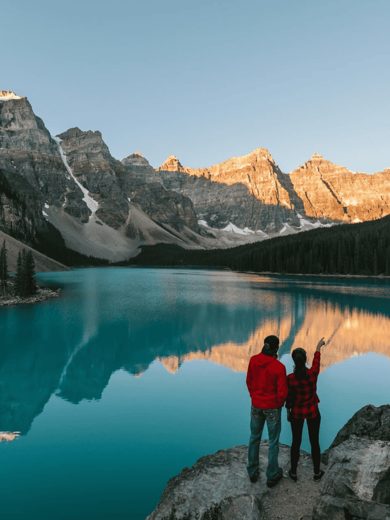 Serene mountain lake with two travelers enjoying scenic views, perfect for adventure and nature exploration.