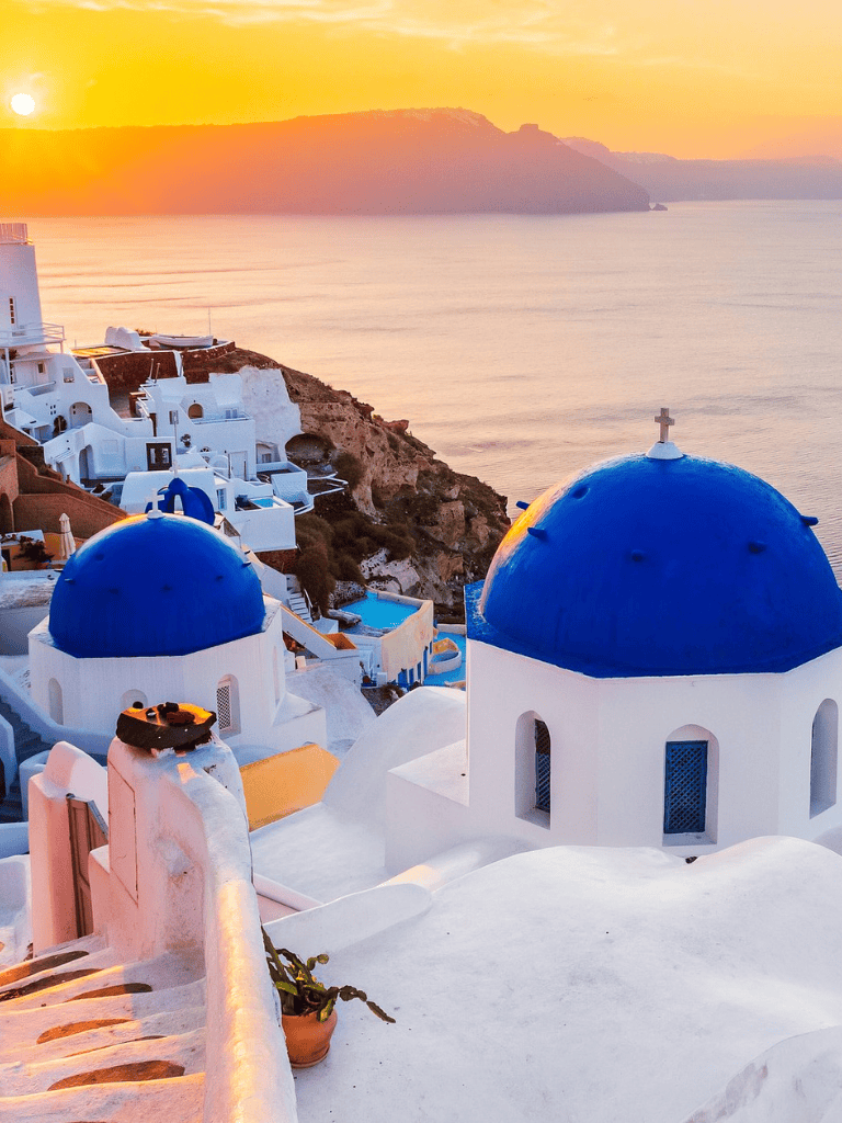 Picturesque Santorini sunset over iconic blue-domed churches and white-washed buildings in Greece.
