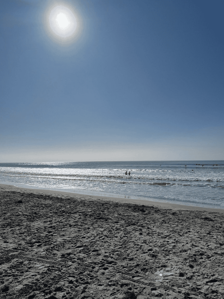 Bright sunny day at the beach with clear blue sky and gentle waves. Perfect for seaside relaxation and ocean adventures.