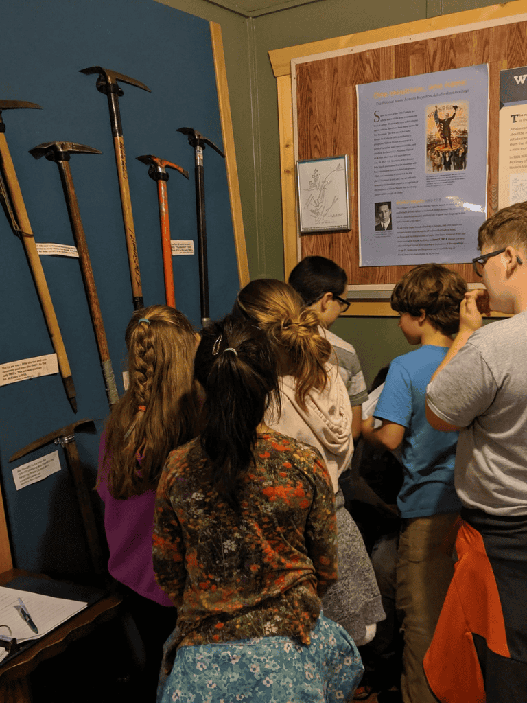 1. Kids exploring historical tools at QuestForDirections museum exhibit.