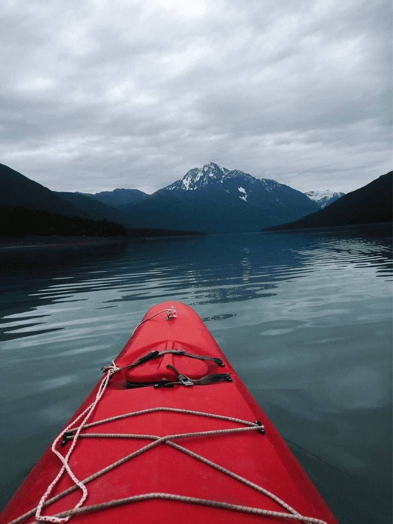 Serene kayaking adventure in mountain lake with snow-capped peaks, ideal for outdoor exploration and nature travel.