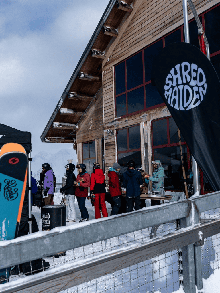 Line 1: Skiers lining up at quest for directions outdoor ski lodge in snowy mountain region.