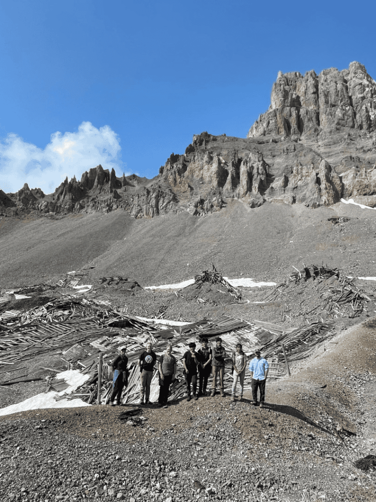 Aerial view of rugged mountain terrain with a group of hikers exploring rocky slopes under blue sky.