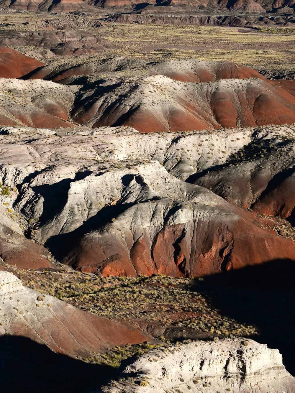 Colorful layered canyon landscape with vibrant red, white, and gray rock formations.