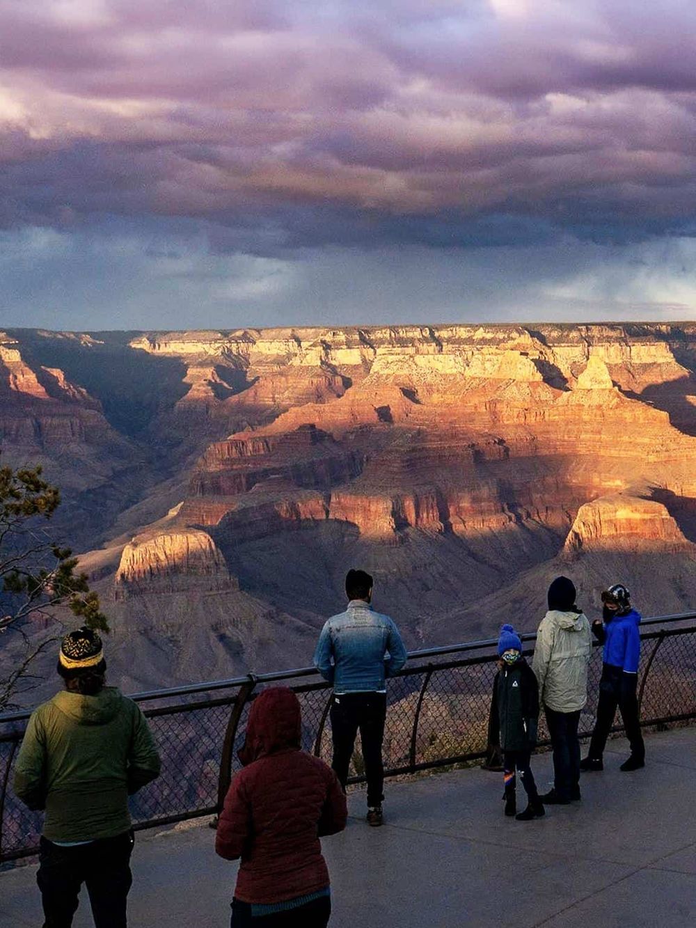 Vibrant sunset at Grand Canyon with visitors enjoying scenic view and breathtaking natural beauty.