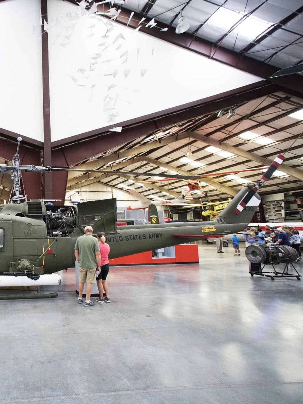 Vintage military helicopter on display at a museum with visitors exploring.