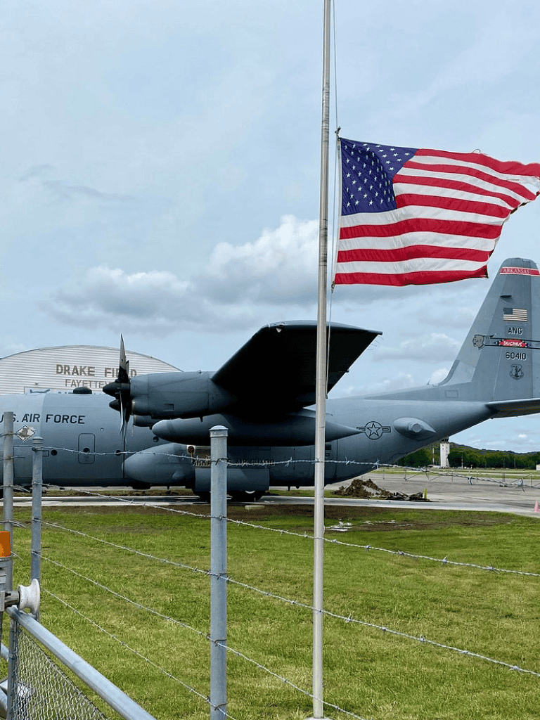 American flag waving near military aircraft at Drake Field.