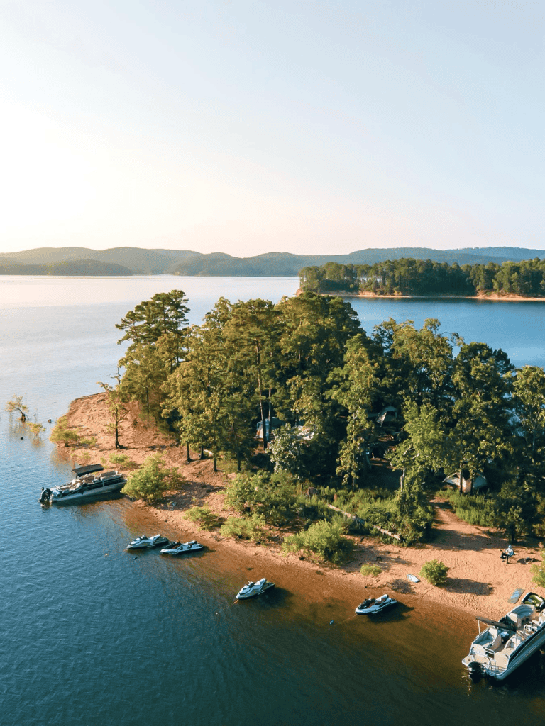 Serene lakeside view with boats, lush trees, and mountain background, ideal for outdoor adventures and nature exploration.