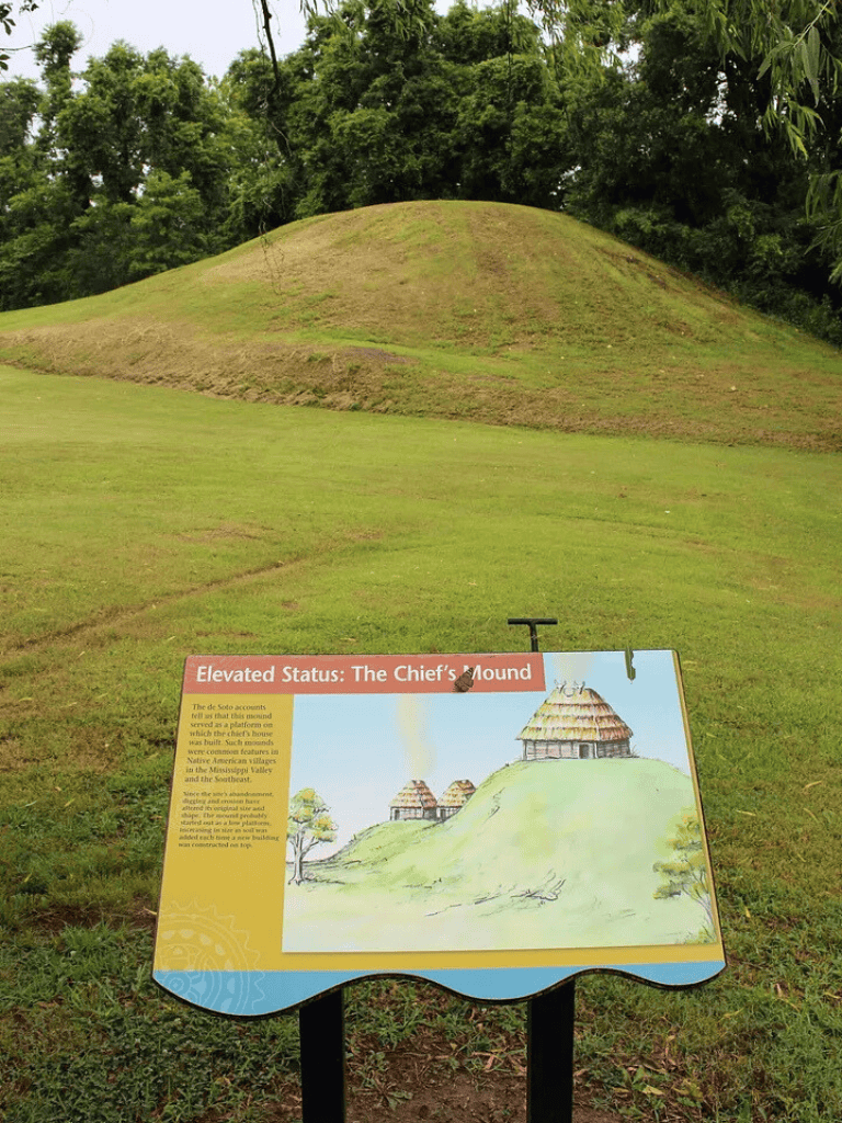 Ancient mound with an informational sign about The Chief’s Mound at a historic site.